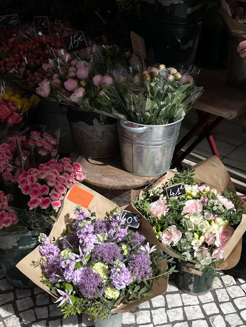 A display of fresh floral arrangements at a flower shop, featuring a variety of bouquets with pink, purple, and white flowers. One bouquet with purple and lavender blossoms, including alliums and lisi